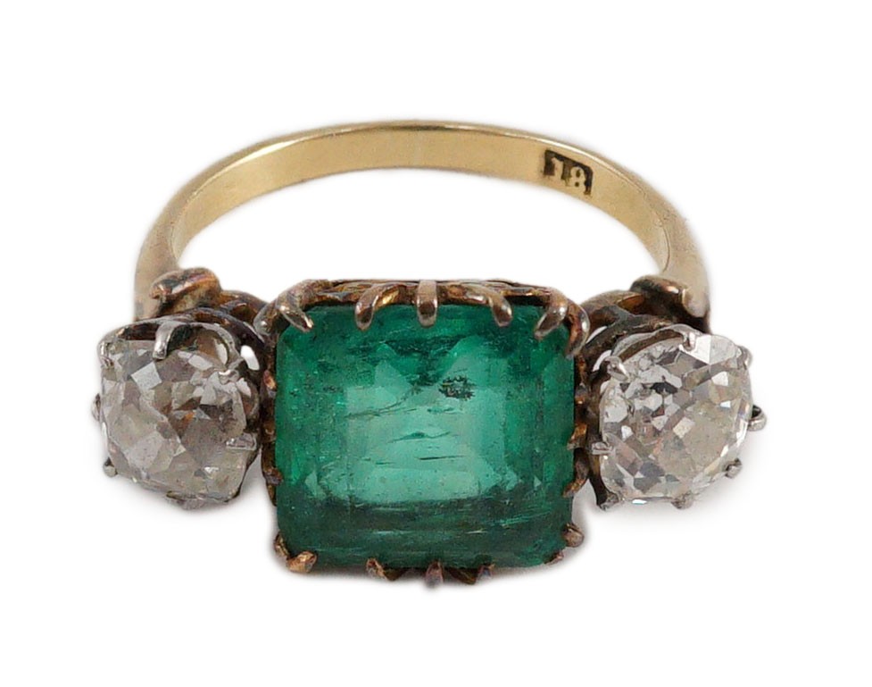 An early 20th century 18ct gold, square cut single stone emerald and two stone cushion cut diamond set dress ring